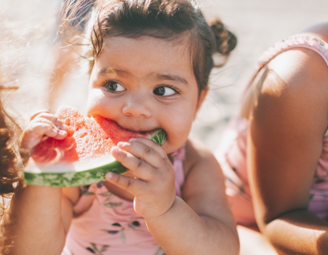 Uma criança comendo uma fatia de melancia