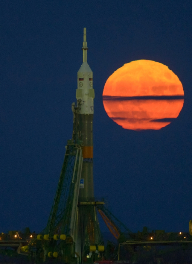 Uma lua laranja brilhante atrás de um foguete 