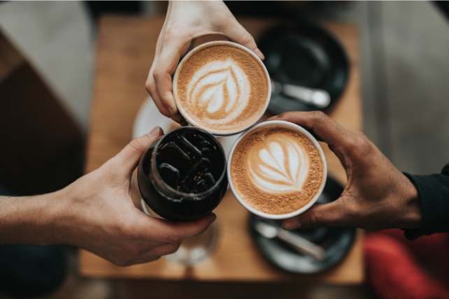 Três cafés sendo segurados pelas mãos