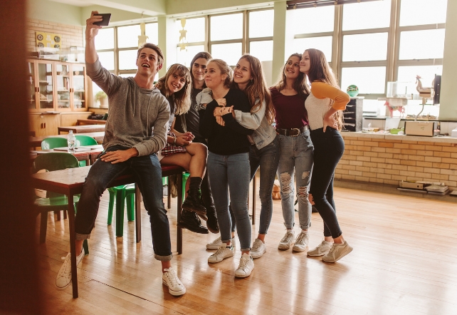 Adolescentes em uma sala de aula tirando uma selfie em grupo