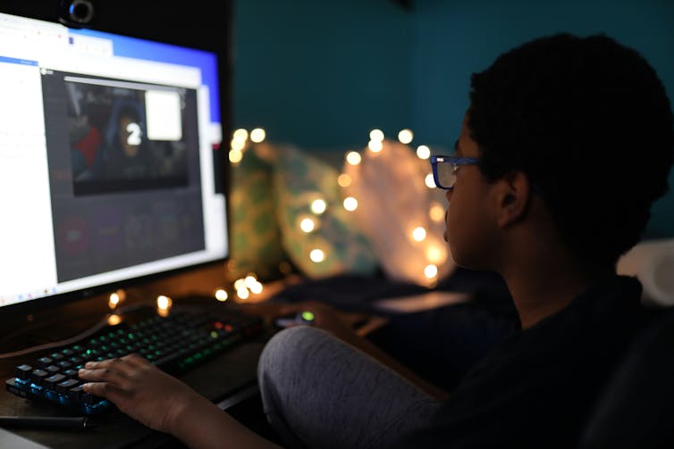 menino senta na tela do computador à noite