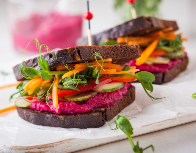 Dois sanduíches em pão de centeio com recheios veganos de cor brilhante